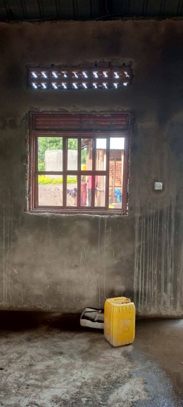 Inside the dormitory: a plastered wall and floor, and a window frame still waiting for glass