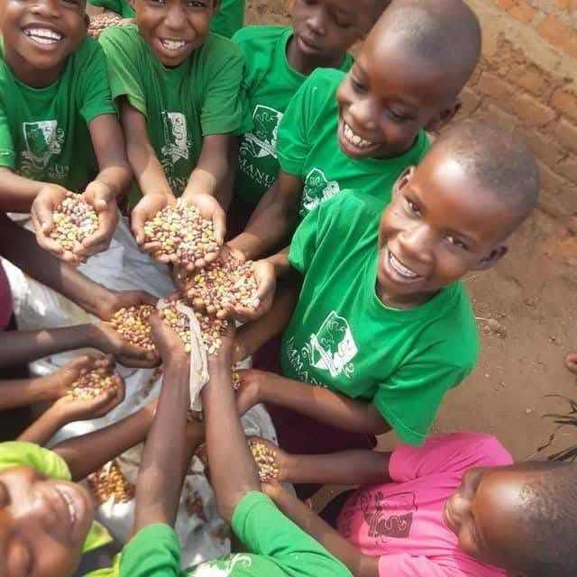 Children in green T-shirts hold out handfuls of food together